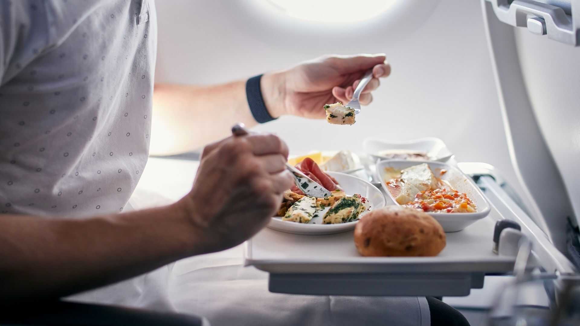 Passager savourant un repas gastronomique à bord d'un vol affrété commercial personnalisé.